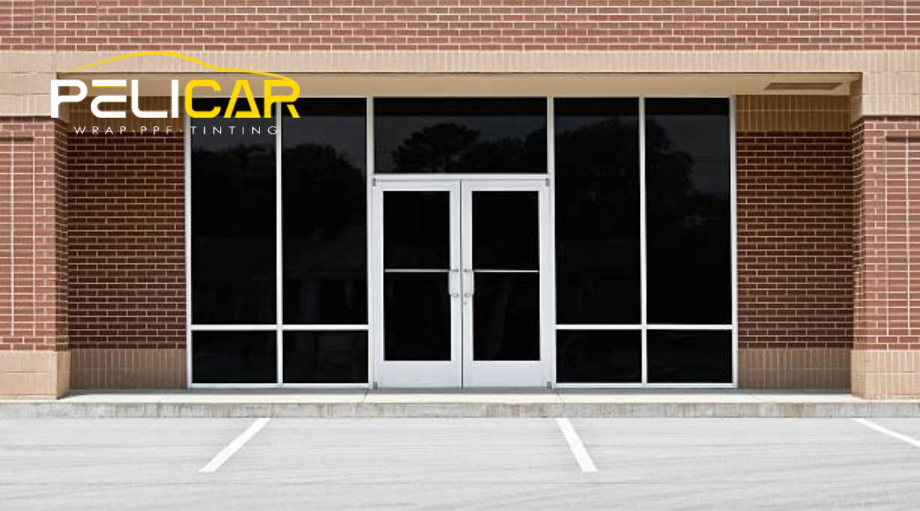 A commercial storefront with large, dark-tinted glass windows and double glass doors, framed by a red brick building. The Pelicar logo is overlaid in the top-left corner, representing their expertise in window tinting solutions.